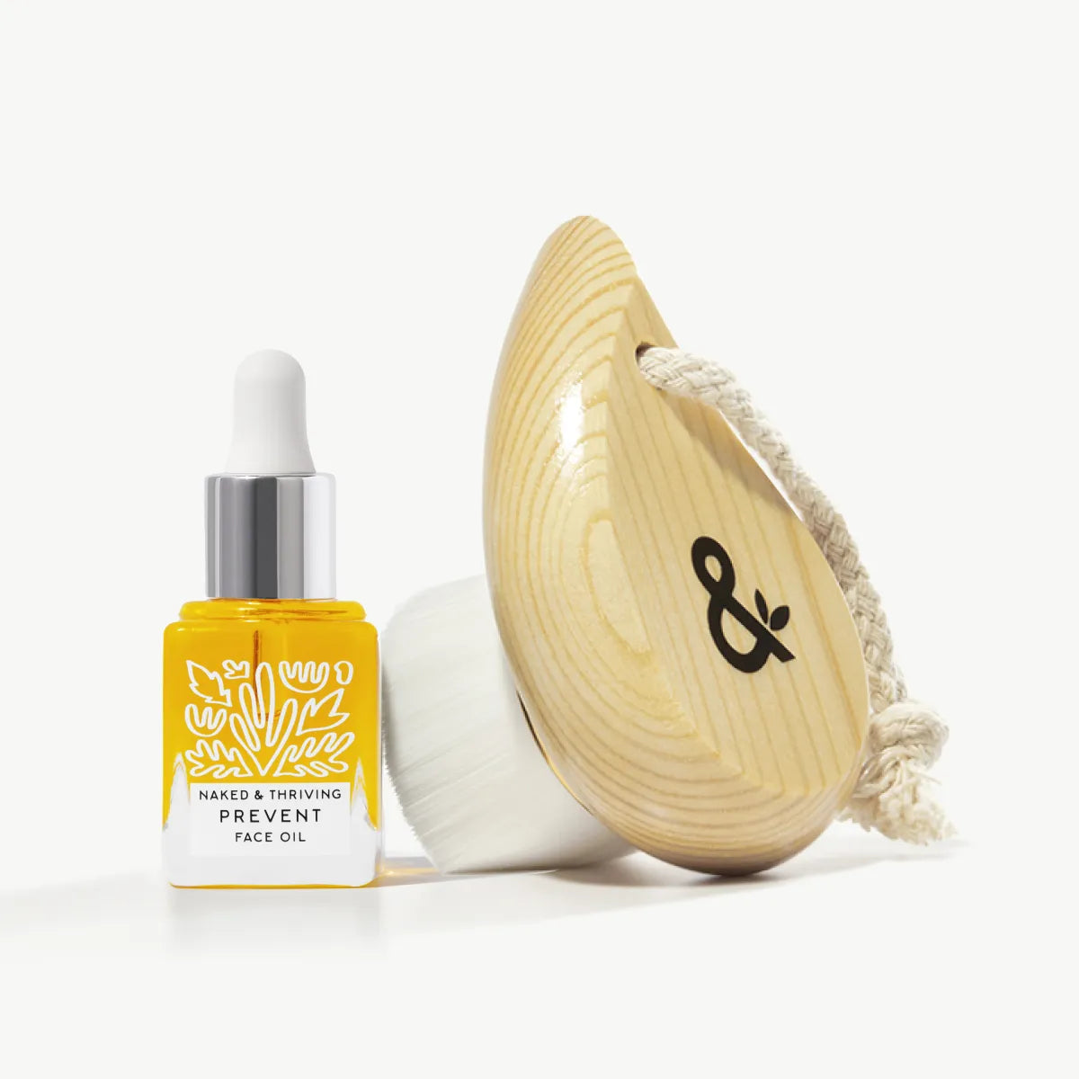 
                
                  Mini Prevent face oil paired with a soft cleansing brush, styled on white
                
              
