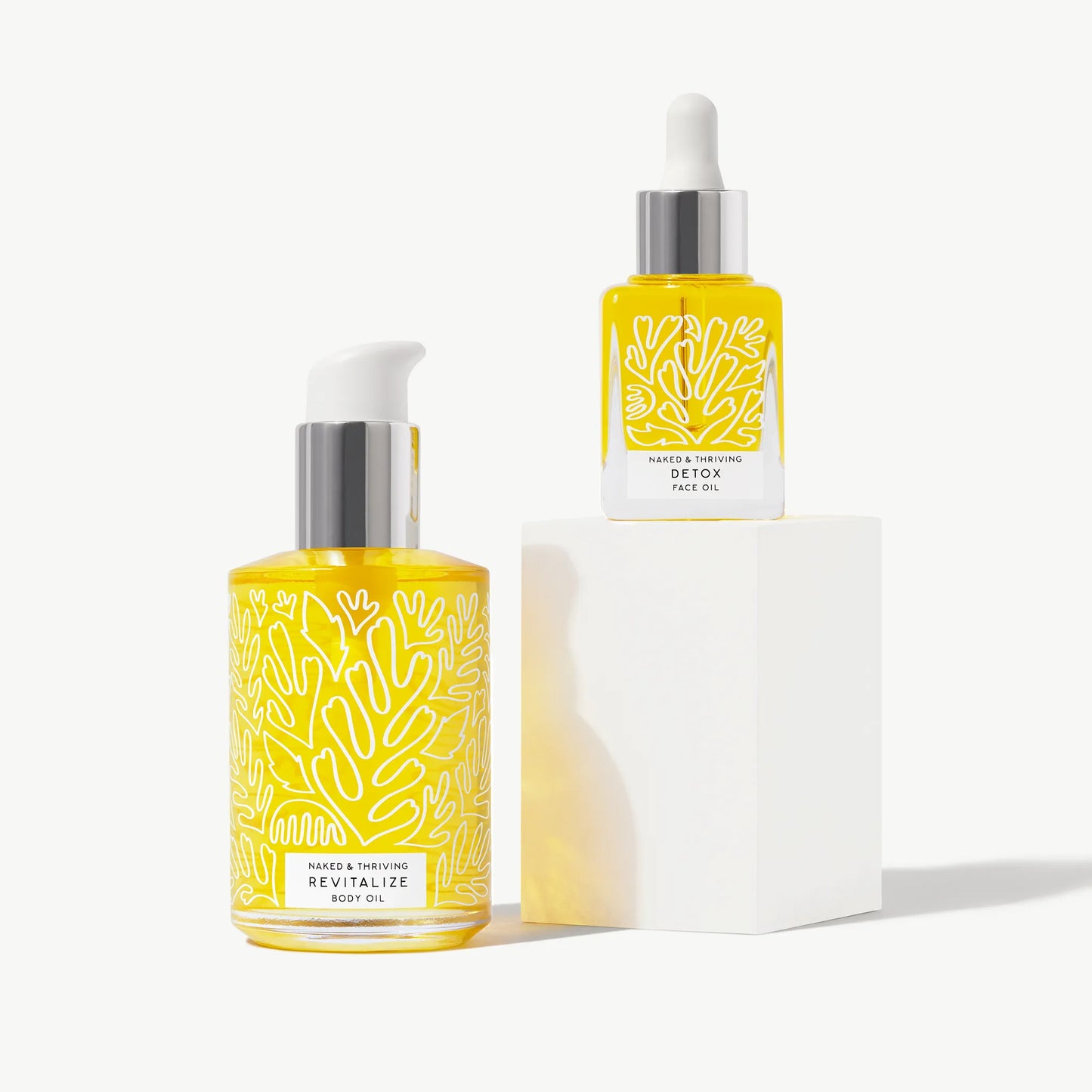 
                
                  Detox face oil and Revitalize body oil bottles arranged on a light background
                
              