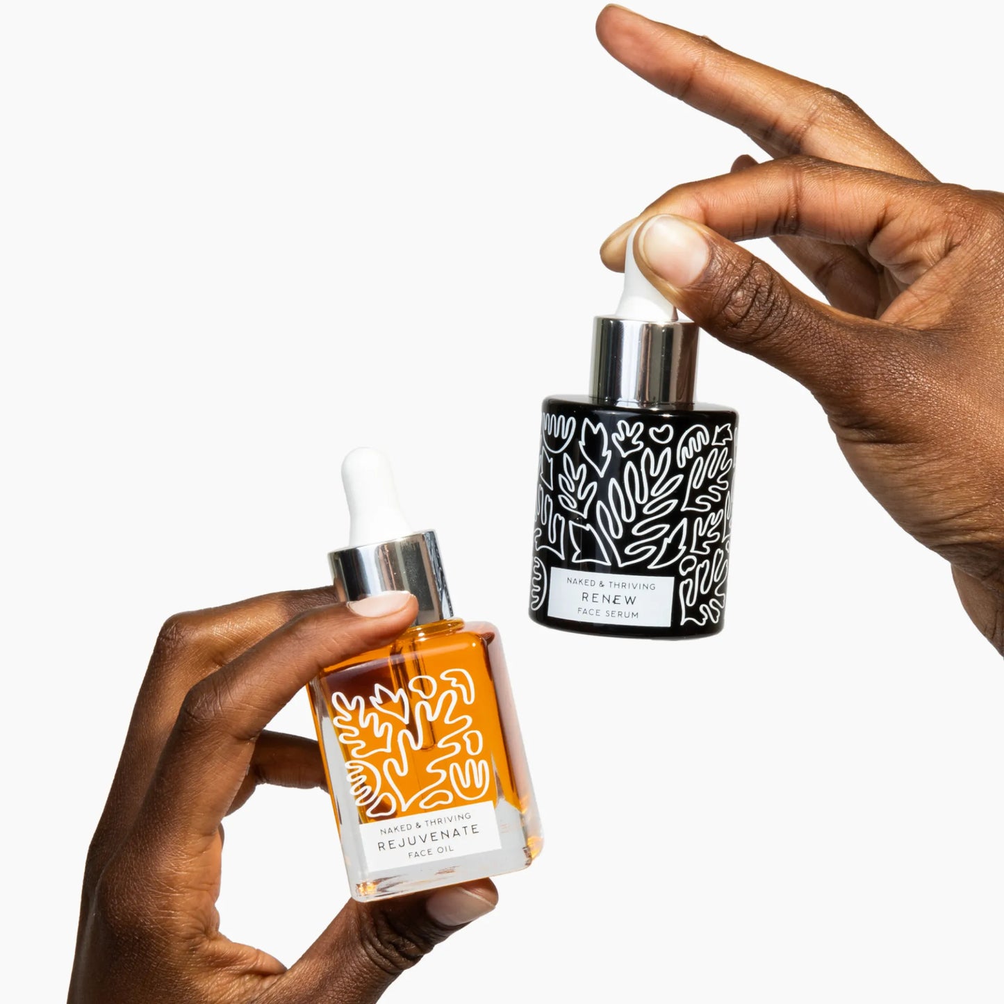 
                
                  Hands holding Rejuvenate Restorative Face Oil and Renew Resurfacing Night Serum dropper bottles against a white background
                
              