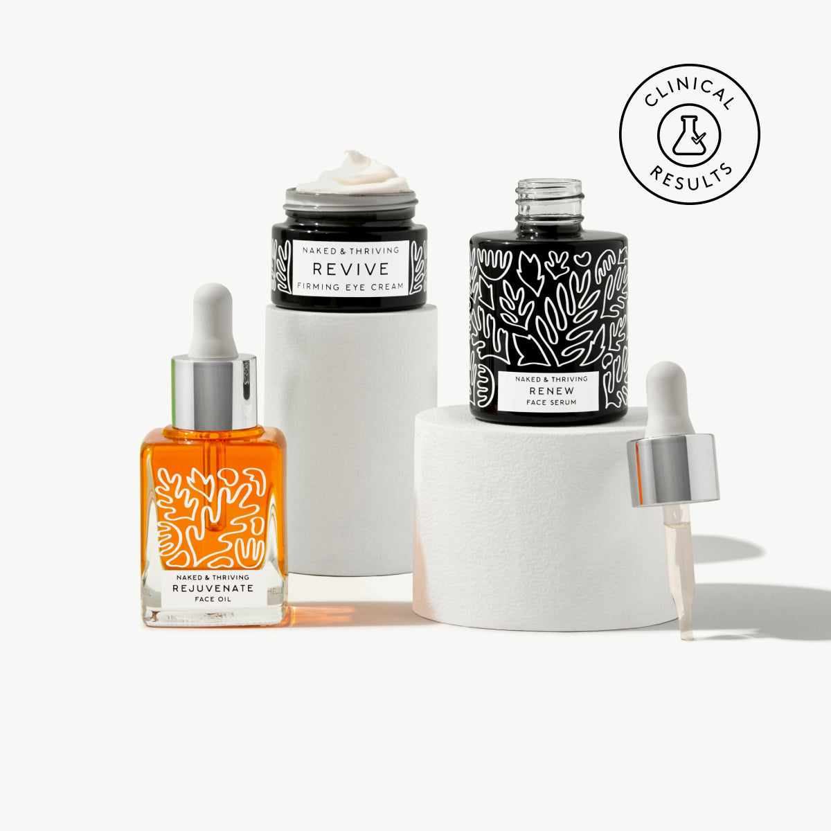 
                
                  Naked & Thriving Restorative Night Routine with botanical-patterned glass dropper bottles and cream jar
                
              