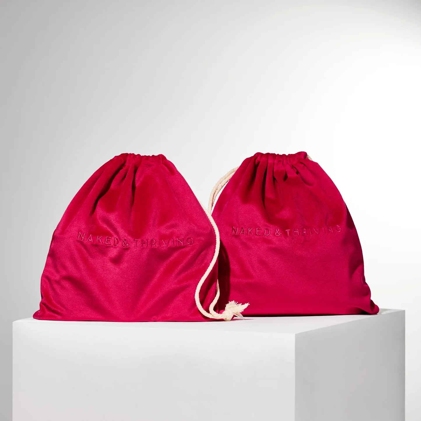 
                
                  Two red fabric drawstring bags photographed on white background
                
              